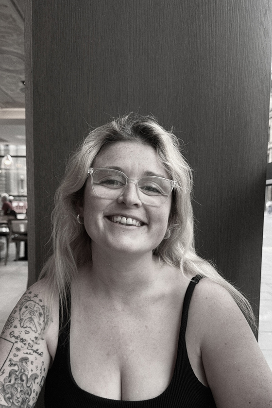 Black-and-white portrait of the smiling With Vic wedding content creator wearing glasses.