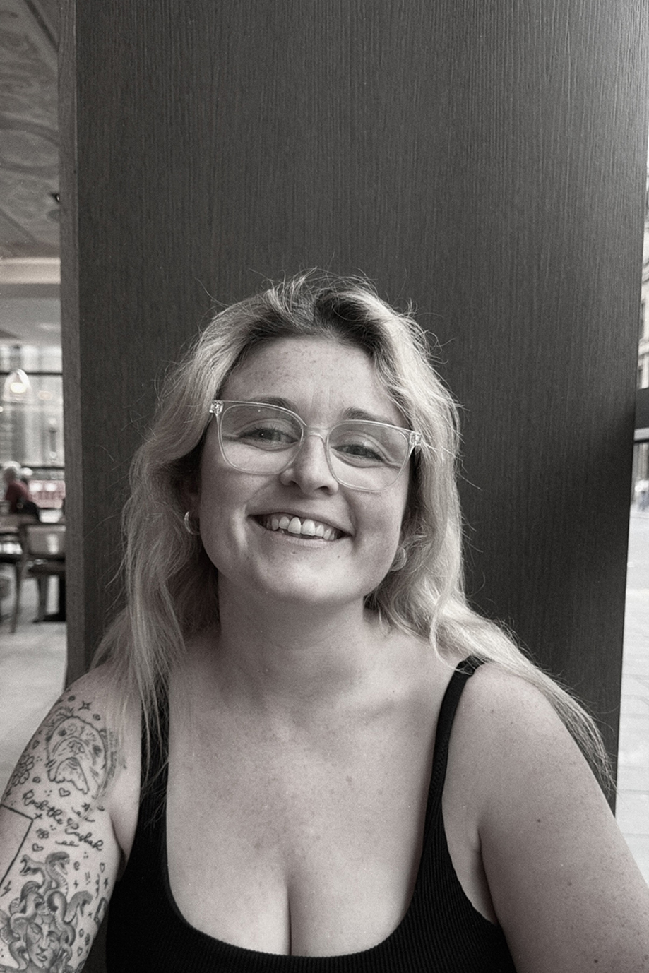 Black-and-white portrait of the smiling With Vic wedding content creator wearing glasses.