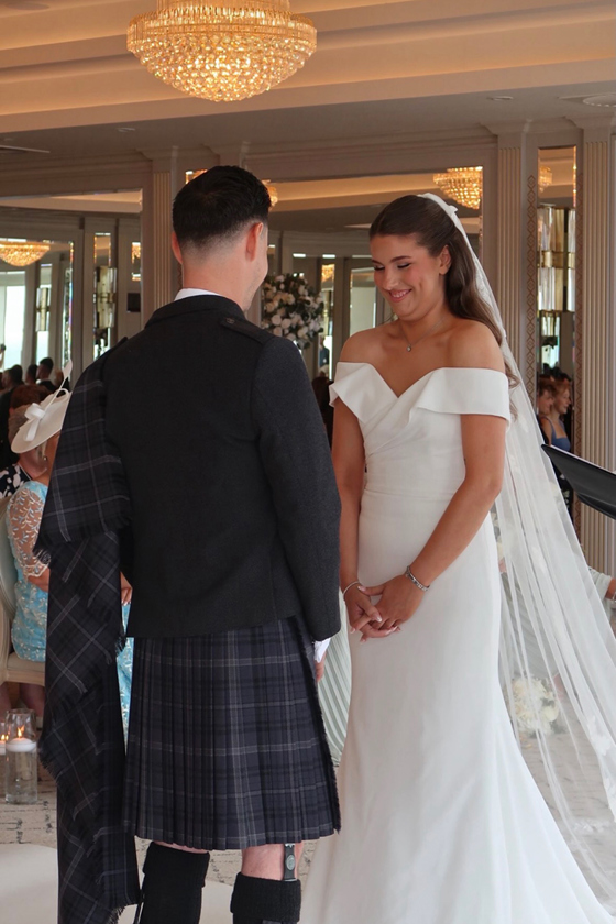 Bride with polished brows and natural bridal beauty look stands opposite the groom during their wedding ceremony.