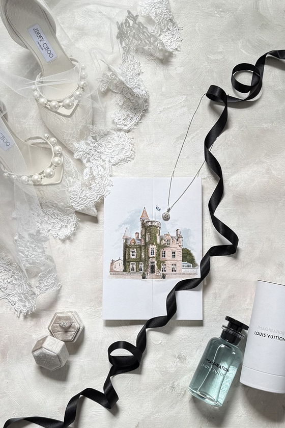 Luxury wedding details flat lay featuring Jimmy Choo bridal shoes, lace veil, rings, jewellery, perfume and venue stationery.