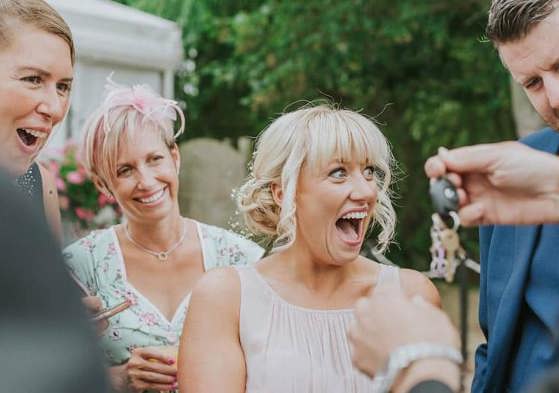 Wedding guests reacting to close-up magic at an outdoor reception