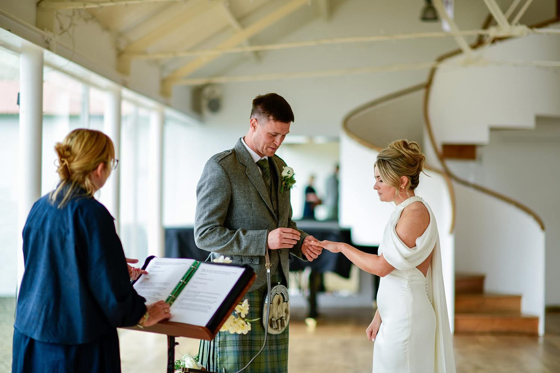 Groom places a wedding ring on the bride’s finger during a ceremony led by Fiona MacAlister Celebrant.