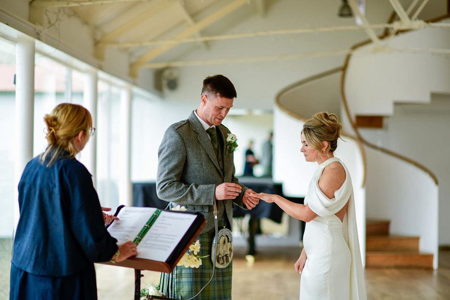 Groom places a wedding ring on the bride’s finger during a ceremony led by Fiona MacAlister Celebrant.