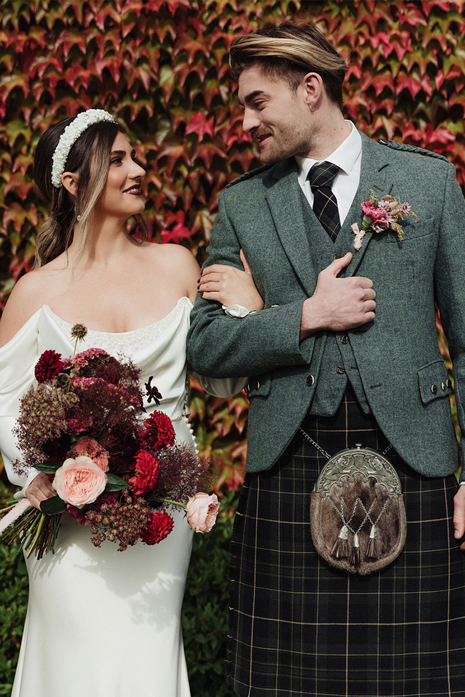 Bride and groom in kilt linking arms and smiling 