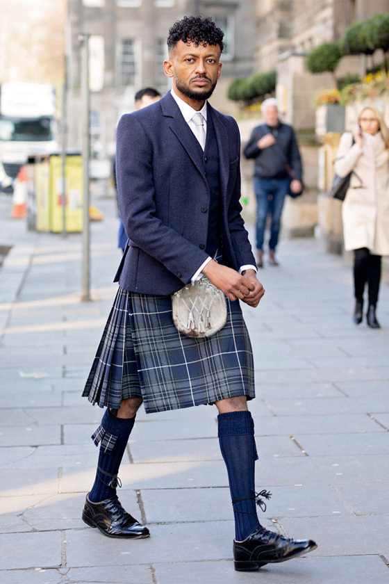 Groom walking wearing navy tartan kilt