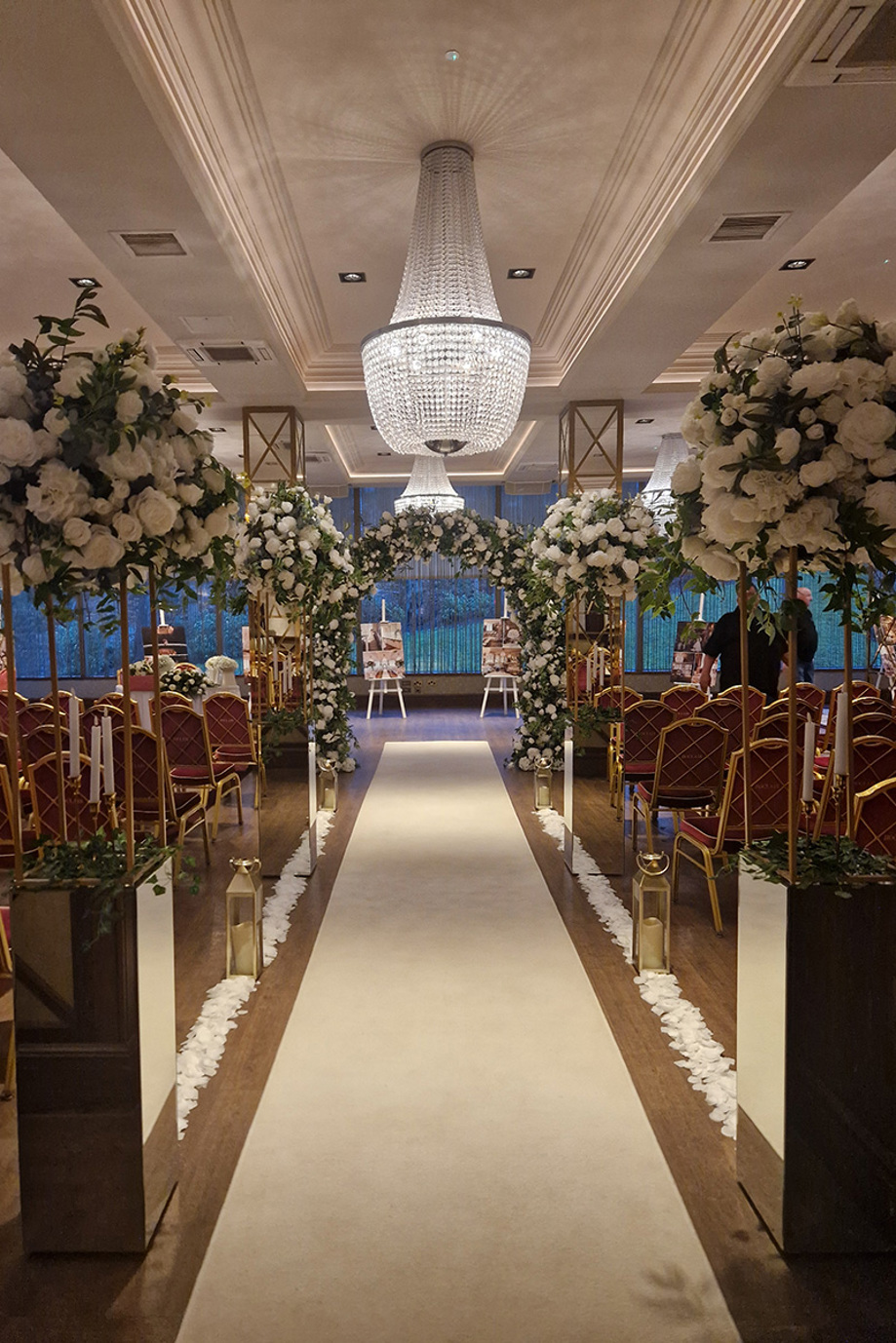 Ceremony aisle decorated with candles, lanterns and floral-topped mirrored pillar boxes