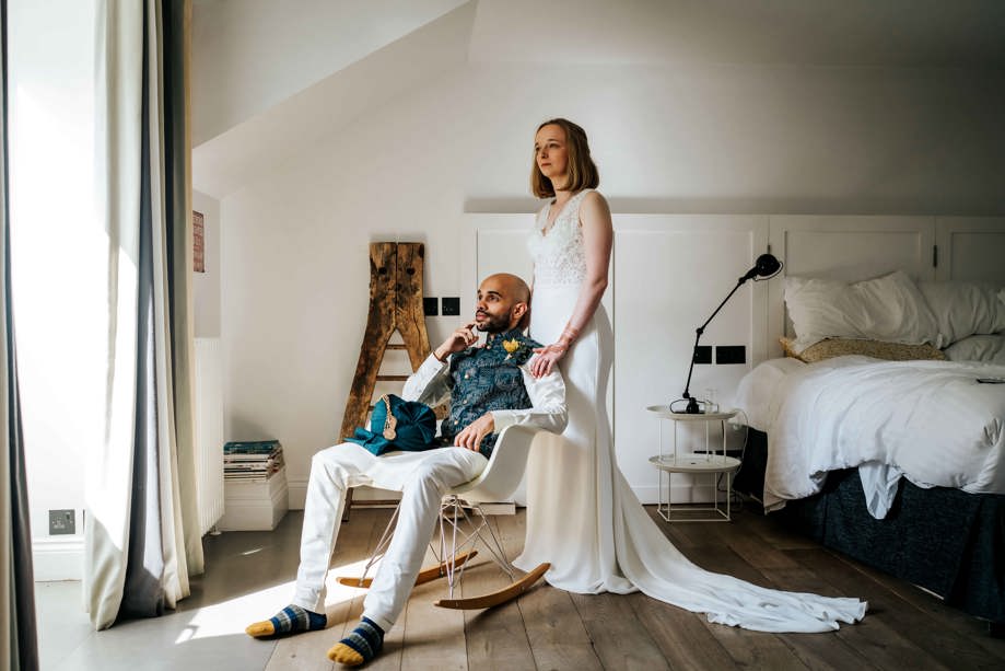 Bride standing behind groom in chair look into distance