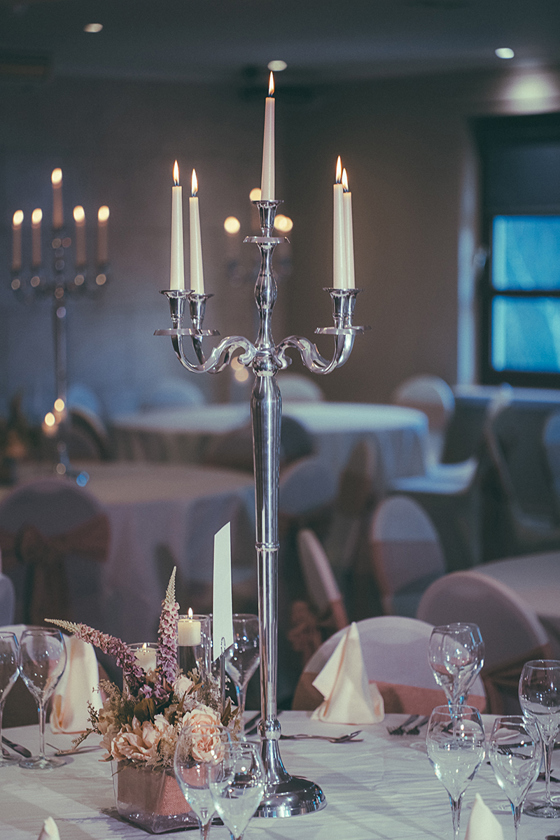 Moody evening image of the silver candelabras used on tables for wedding meals at The River Inn near Glasgow, with flowers and other table decor around.