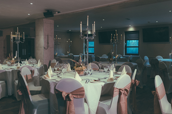 Wedding meal set up in the Crosslee Suite at The River Inn in Houston, Renfrewshire, with pink bows on chairs and silver candelabras.