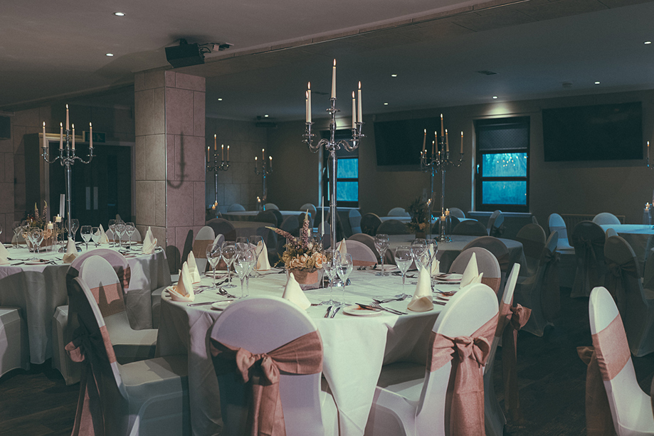 Wedding meal set up in the Crosslee Suite at The River Inn in Houston, Renfrewshire, with pink bows on chairs and silver candelabras.