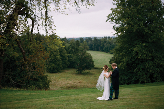 Bride and groom stand together on lawns of Newton Don Estate in Kelso, Scottish Borders.