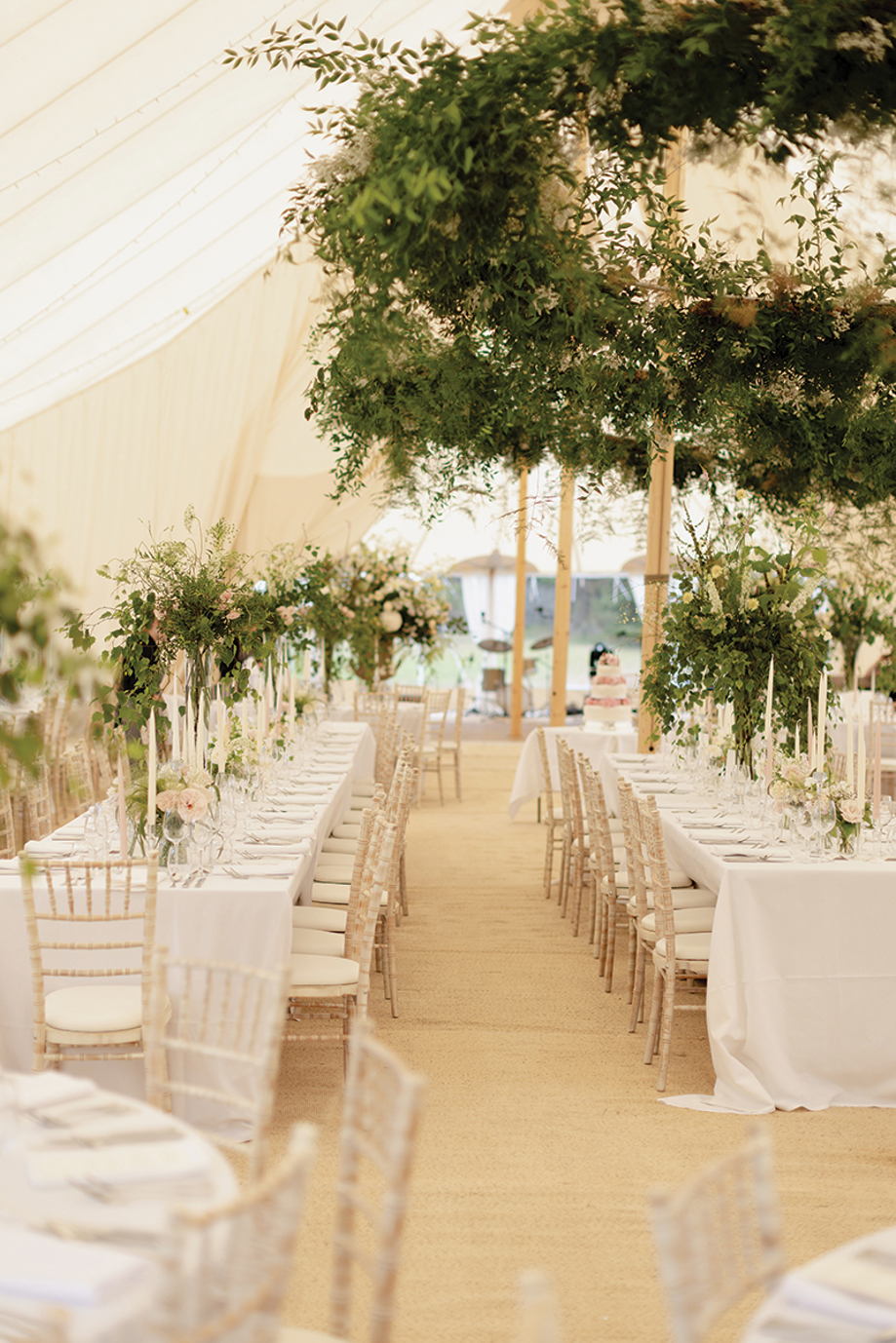 Image of long tables with large leafy floral installations inside marquee at Newton Don Estate.