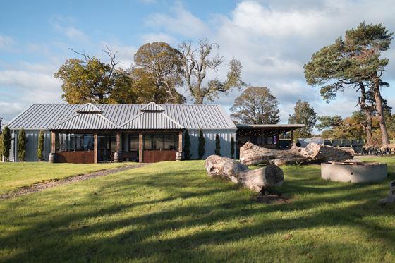 The Venue @ Duntarvie Castle exterior with landscaped lawns, firepit area and modern barn reception space in the Scottish countryside.