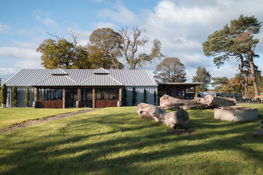 The Venue @ Duntarvie Castle exterior with landscaped lawns, firepit area and modern barn reception space in the Scottish countryside.