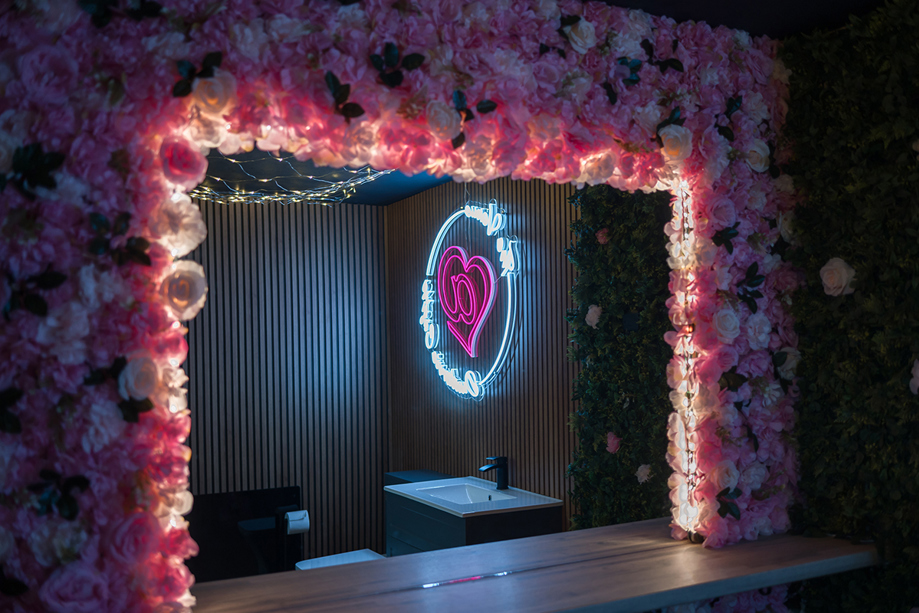 Stylish bridal restroom at The Venue @ Duntarvie Castle with pink floral frame mirror and neon heart sign, modern wedding venue detail.