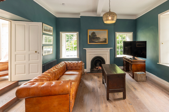 Cosy lounge at Broomholm Manor featuring a leather Chesterfield sofa, fireplace and elegant country house interiors.