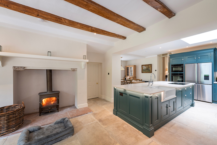 Spacious country house kitchen at Broomholm Manor with kitchen island, wood-burning stove and modern amenities.
