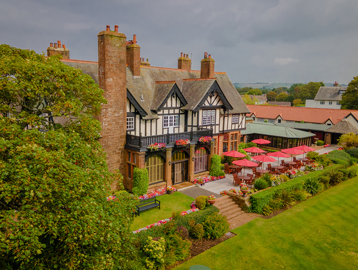 Exterior of Piersland House wedding venue with landscaped gardens, terrace seating and red parasols