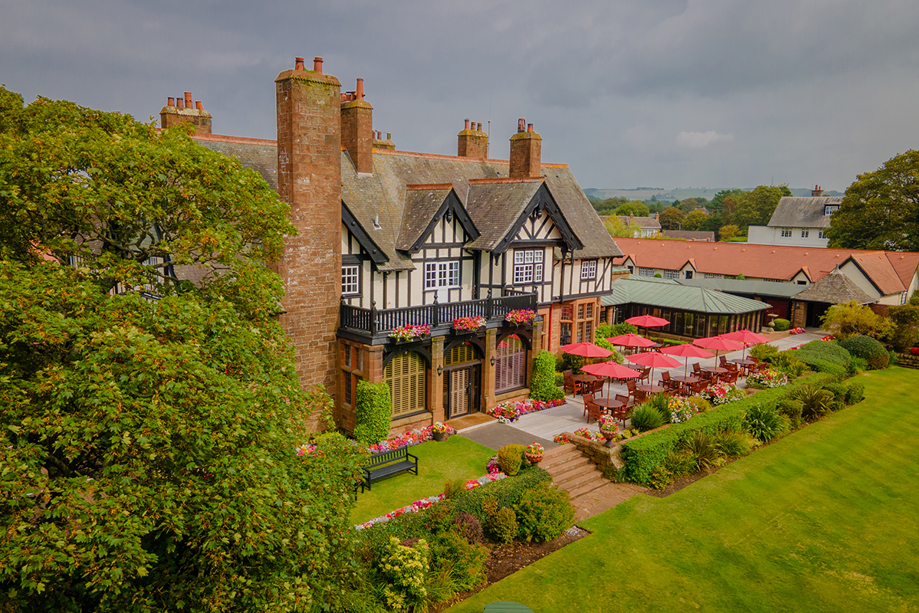 Exterior of Piersland House wedding venue with landscaped gardens, terrace seating and red parasols