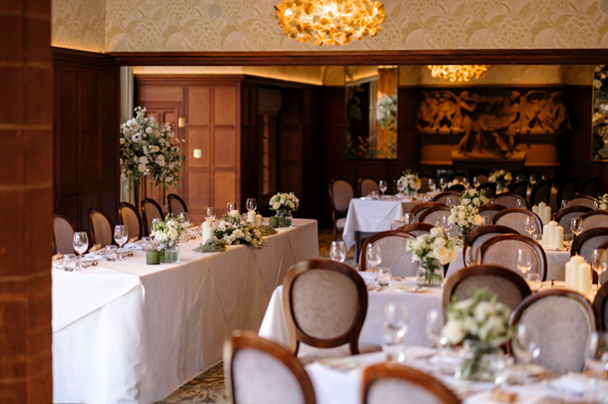 Wedding breakfast setup at Piersland House with white table linens, floral centrepieces and candles