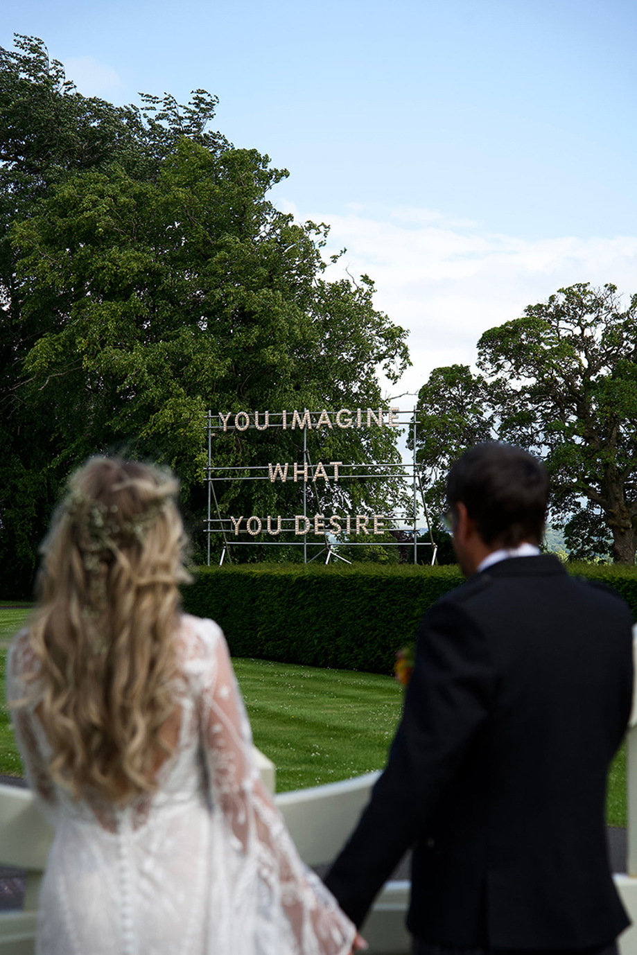 Newlywed couple looking towards an outdoor light installation in the grounds of Jupiter Artland