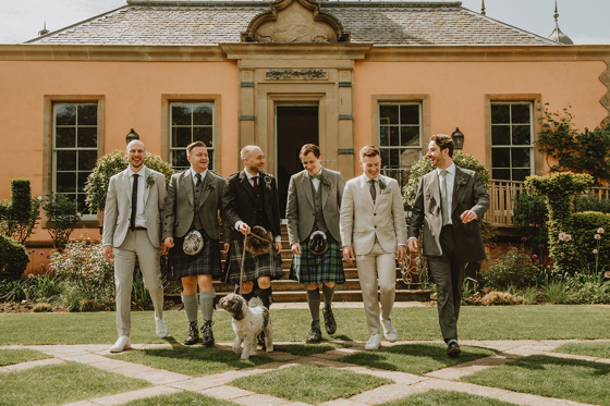 Groom and groomsmen walking with a dog through the gardens at Jupiter Artland wedding venue