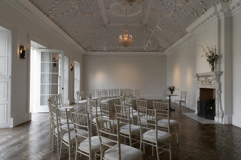 Indoor wedding ceremony setup at Jupiter Artland with Chiavari chairs, parquet flooring and ornate plaster ceiling