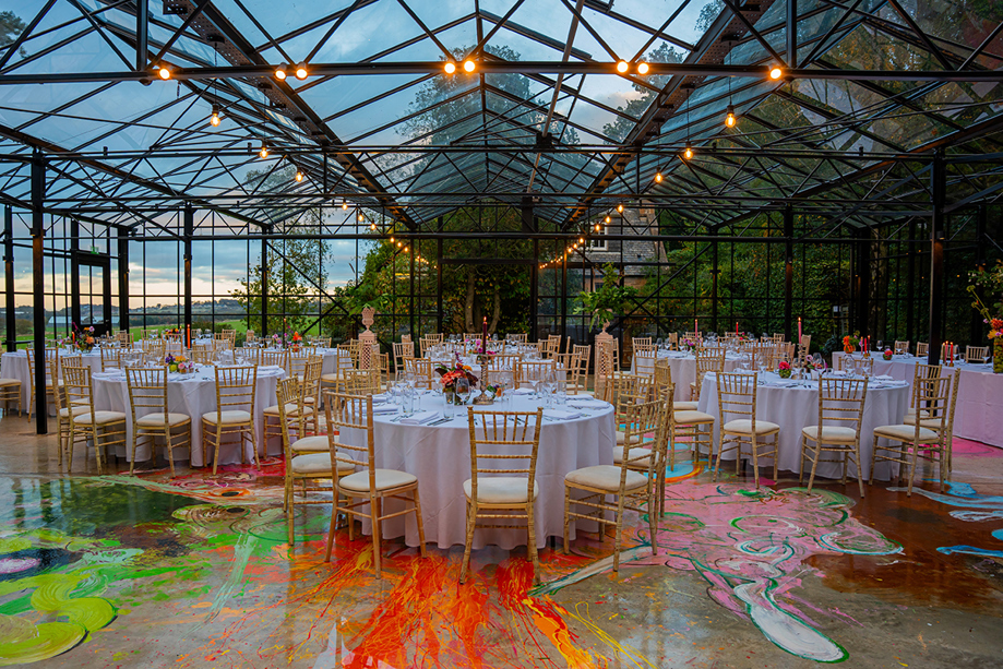 Jupiter Artland wedding reception setup with round tables, gold Chiavari chairs and colourful painted flooring