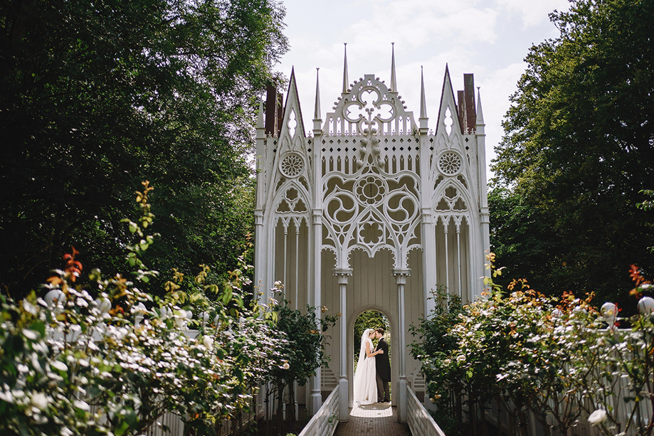 Newlywed couple kissing beneath a white sculptural installation in the gardens at Jupiter Artland