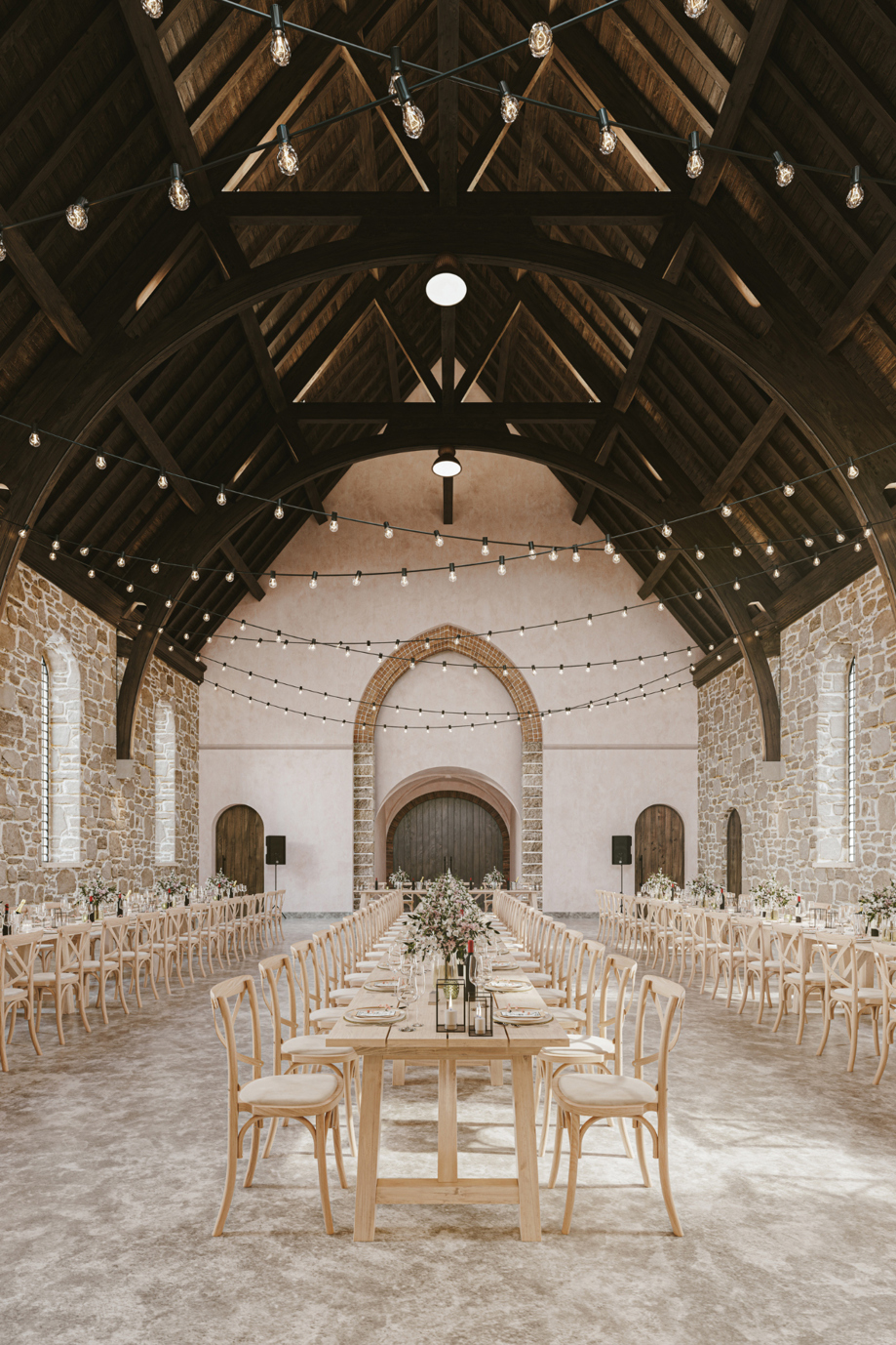 Grand Hall at The West Works Glasgow set for a wedding breakfast, with long wooden tables, floral centrepieces and festoon lighting