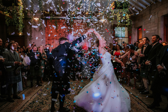 Groom spins his bride around on the dancfloor with confetti falling around them
