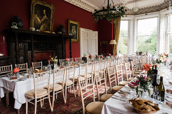 Long tables decorated with orange flowers for wedding meal 