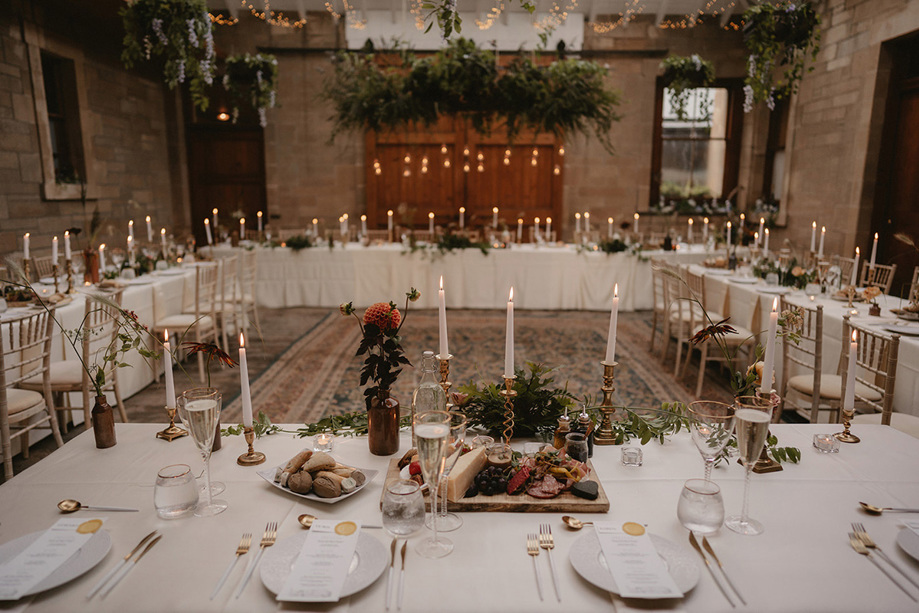 Long tables set out in square format with candlesticks and leafy decor