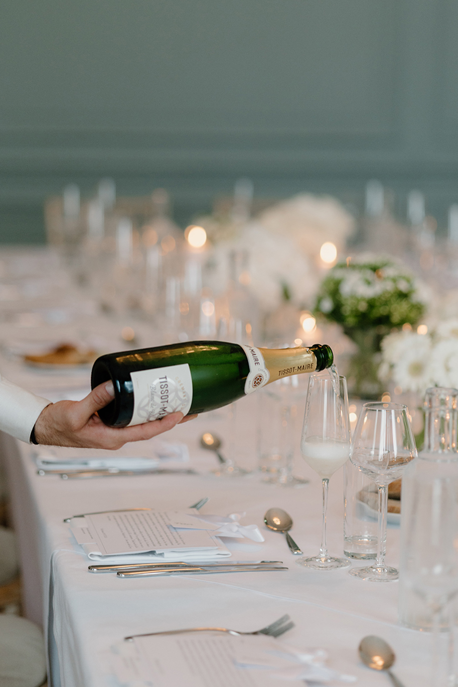 Champagne being poured at a wedding reception table at The Edinburgh Grand, surrounded by candles and white flowers.