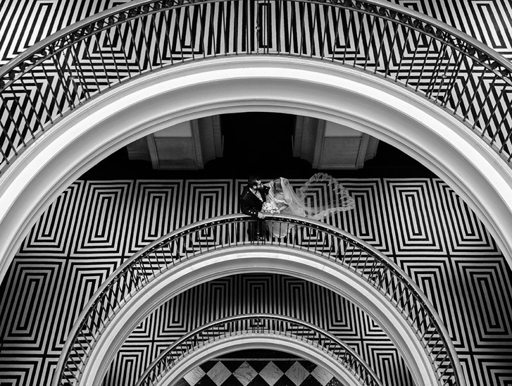 Black-and-white portrait of newlyweds on the distinctive curved staircase at The Edinburgh Grand.