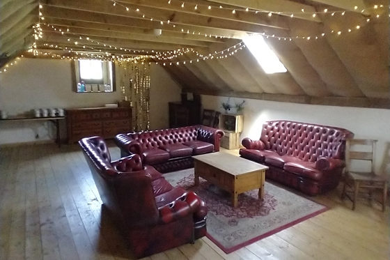 Hayloft lounge at Cormiston Farm with leather sofas, exposed beams and fairy lighting