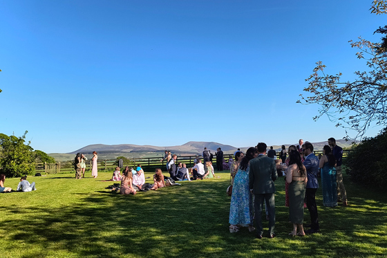 Wedding guests mingling on the lawn at Cormiston Farm with rolling hills in the background