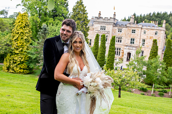 Bride and groom smile on the grounds of Crossbasket Castle