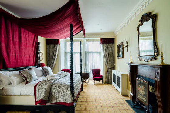 The Tower Suite with red and gold accents, ornate fireplace and four poster bed