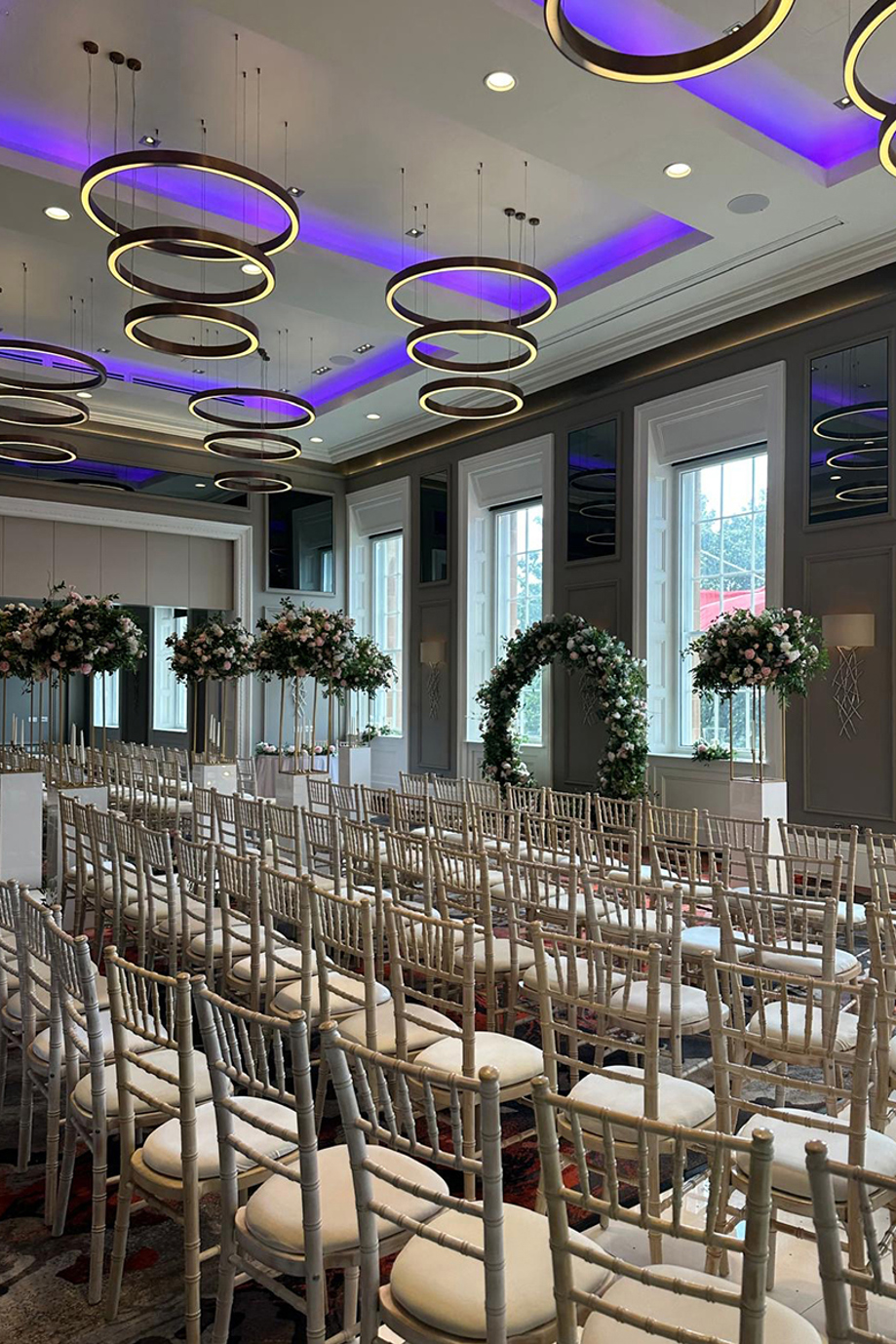 Side view of a ceremony at The Clayton Hotel, with a flower hoop and purple lights on ceiling