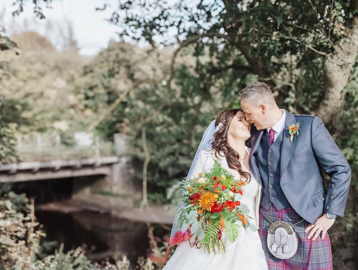 Bride and groom portrait in the woodland grounds at Dalgarven House with autumn bouquet and groom in kilt