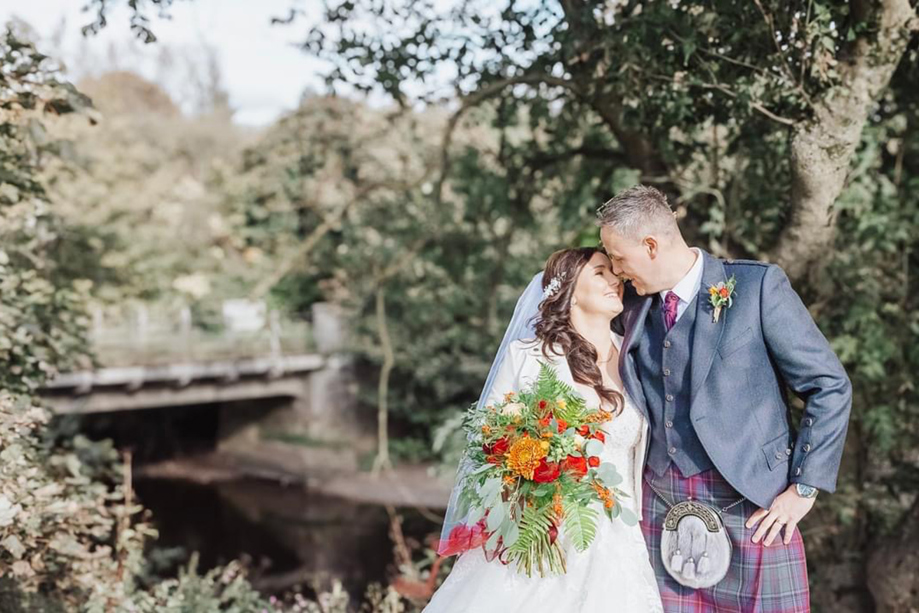 Bride and groom portrait in the woodland grounds at Dalgarven House with autumn bouquet and groom in kilt
