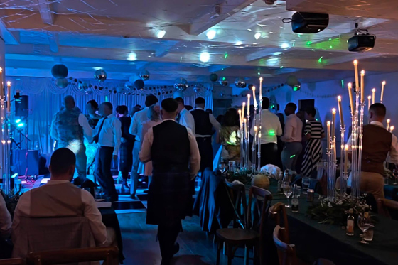 Evening wedding reception at Dalgarven House with guests dancing, blue lighting, disco balls and candlelit tables