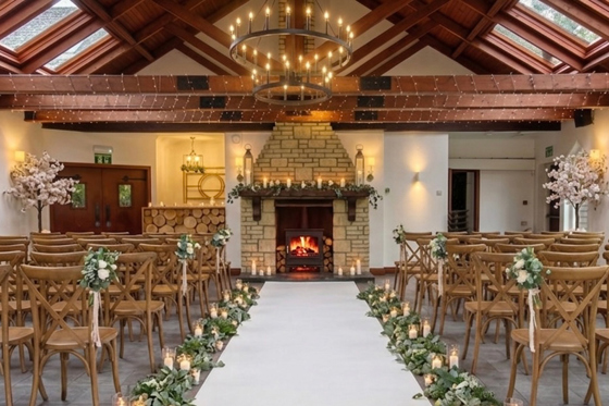 Indoor wedding ceremony at Dalgarven House with fireplace, wooden chairs, aisle flowers and candlelit décor