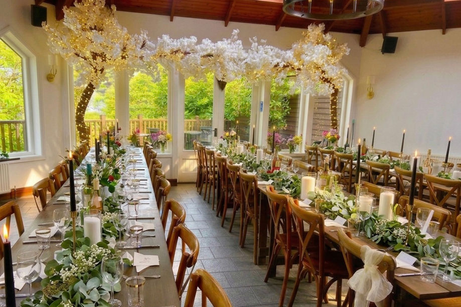 Orangery wedding reception at Dalgarven House with banquet tables, greenery garlands, candles and blossom trees