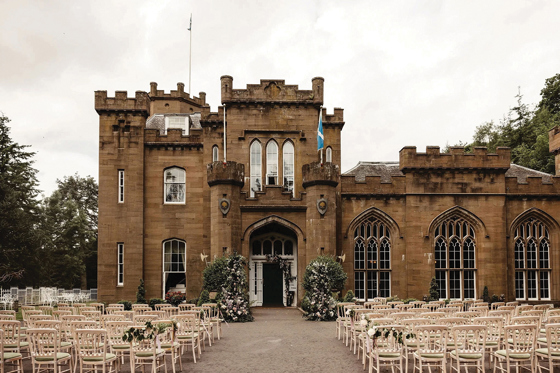 Outdoor wedding ceremony set up at the entrance of Drumtochty Castle, Aberdeenshire, with guest seating and floral styling.