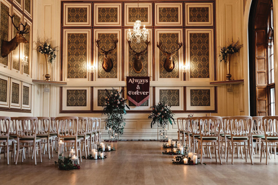 Wedding ceremony set-up in a traditional panelled room at Drumtochty Castle, featuring candles and floral arrangements.