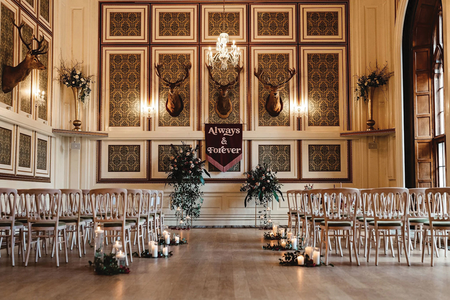 Wedding ceremony set-up in a traditional panelled room at Drumtochty Castle, featuring candles and floral arrangements.