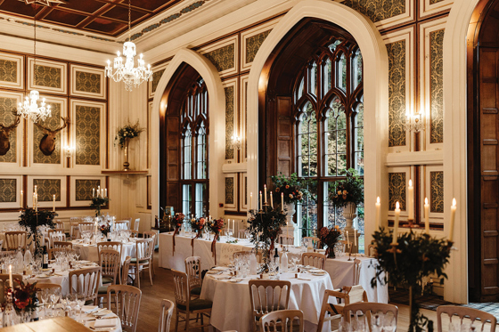 Wedding reception dining set-up at Drumtochty Castle with long tables beside tall arched windows.