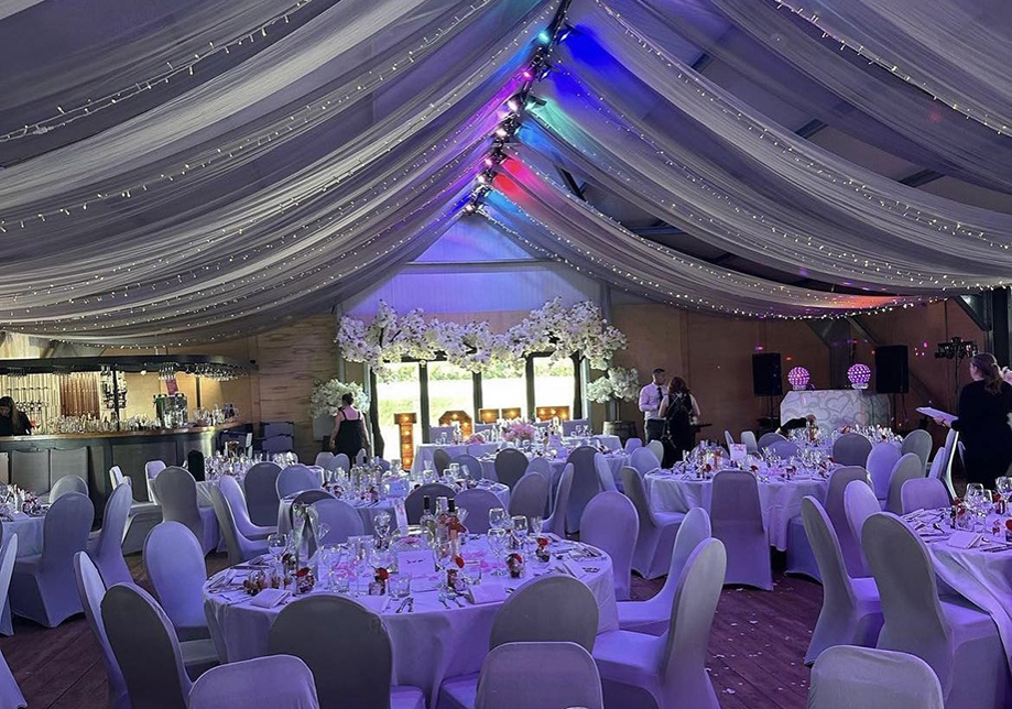 Wedding meal set up with draped rainbow fairy light decorated ceiling